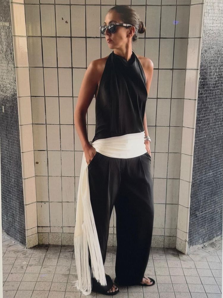 Hanna MW wears black trousers, white fringe scarf as belt and black halter neck top