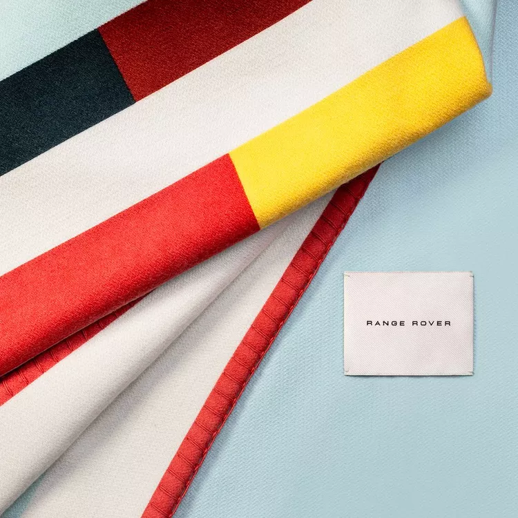 Range Rover British Summertime Collection Courtside Blanket in tennis-inspired stripes, folded to show the Range Rover label.