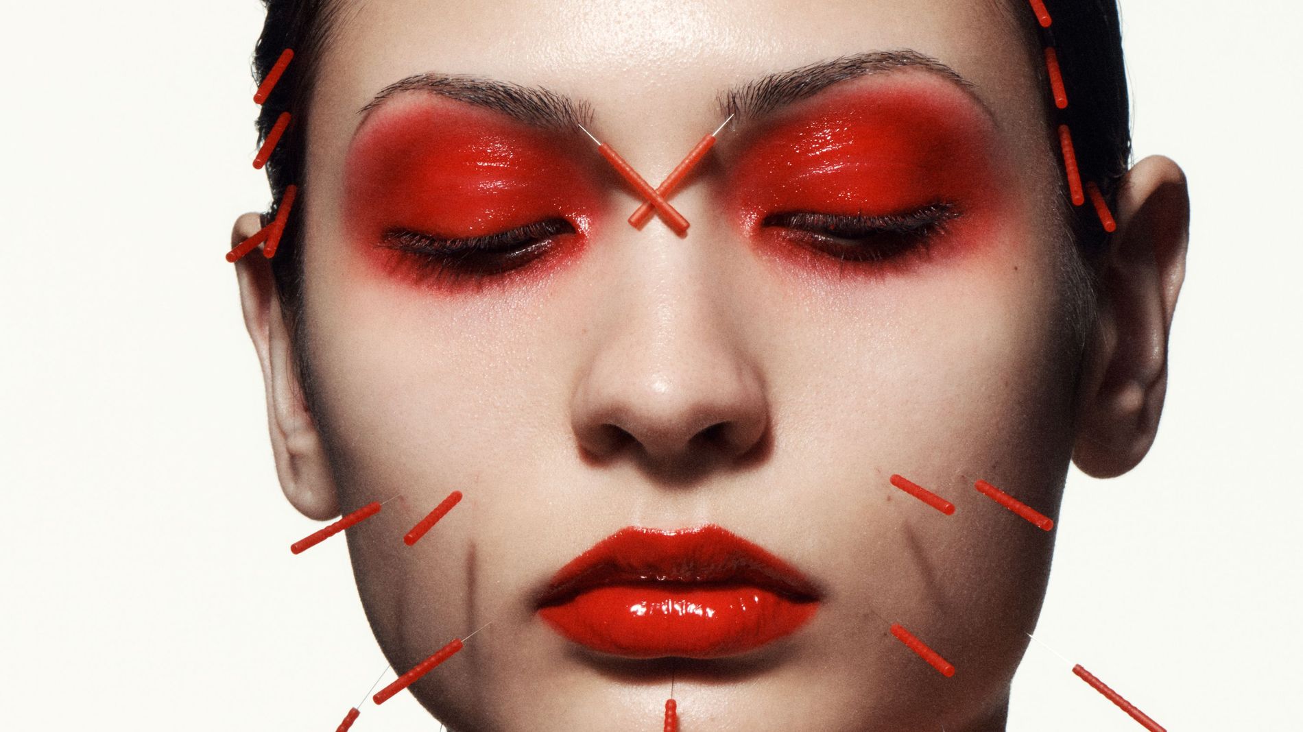 Model wearing red makeup and red acupuncture needles