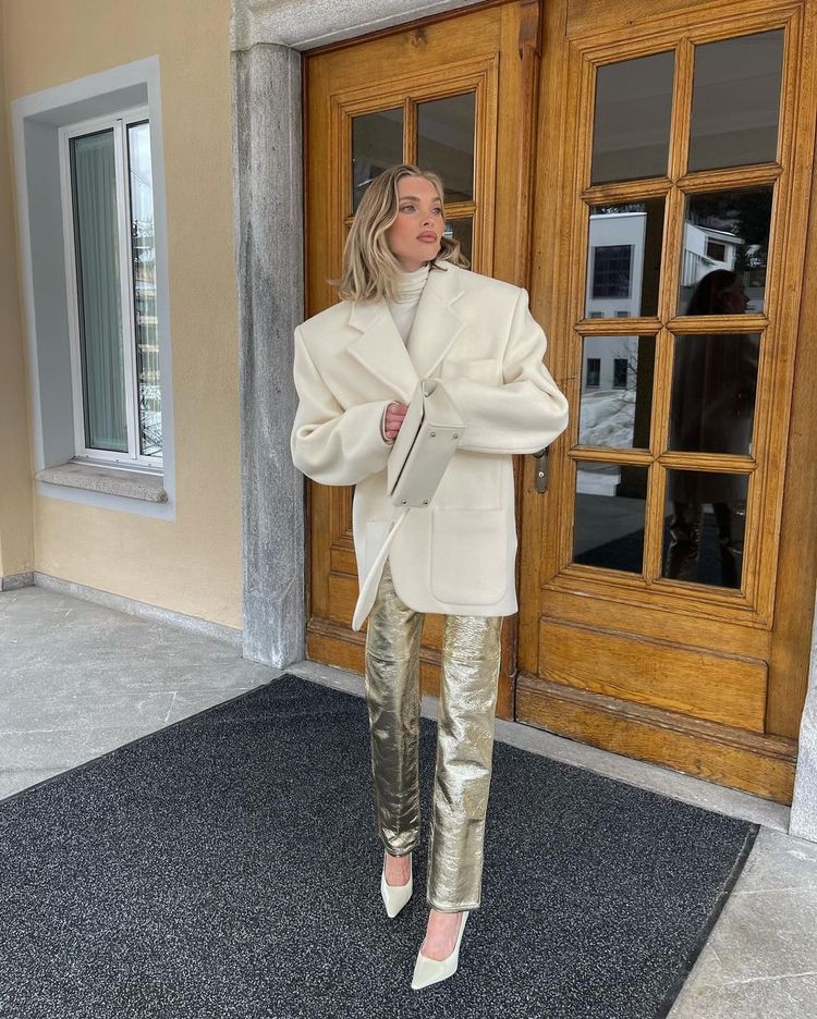 Elsa Hosk wears a thick cream blazer coat with gold trousers and white heels
