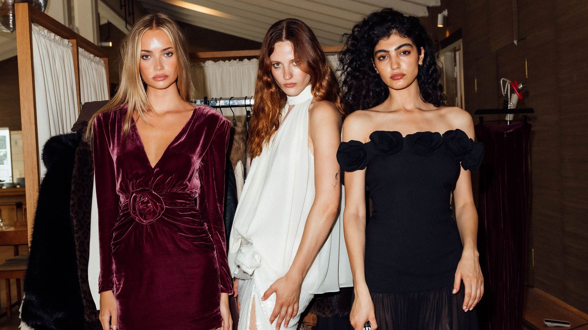 Models backstage at Rotate's CPHFW presentation: Left wears dark red velvet mini dress, middle wears white maxi dress, right wears black maxi dress